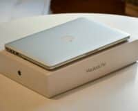 A MacBook Pro laptop placed on its original packaging on a white indoor table.